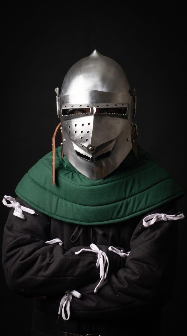 Houndskull bascinet helmet with green padded coif worn on fighter, front three-quarter view showing perforated visor and leather chin strap