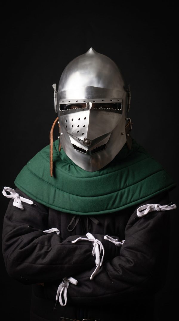 Houndskull bascinet helmet with green padded coif worn on fighter, front three-quarter view showing perforated visor and leather chin strap