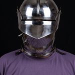 15th century armet helmet front view worn on fighter showing open visor with horizontal sight slit, rounded skull with raised medial ridge, and integrated articulated gorget lames, steel combat helmet for SCA and Buhurt
